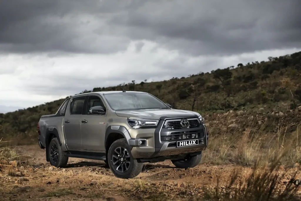 Toyota Hilux Travel pickup in rugged terrain showing bold front grille and LED headlamps